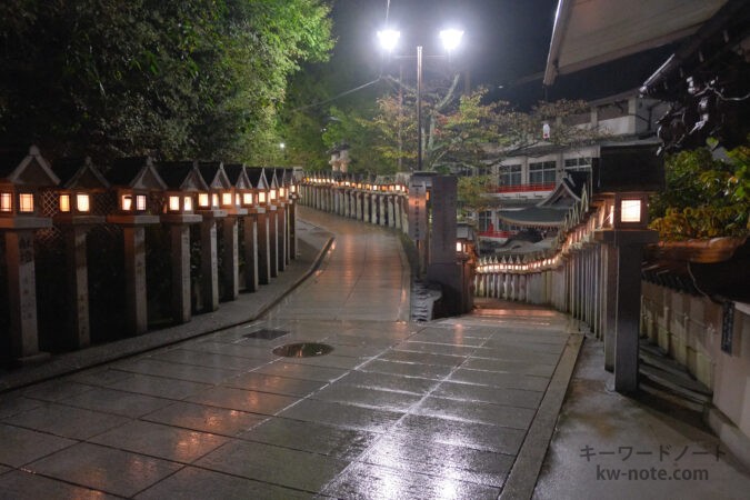 雨で湿った通路に反射する灯篭の光